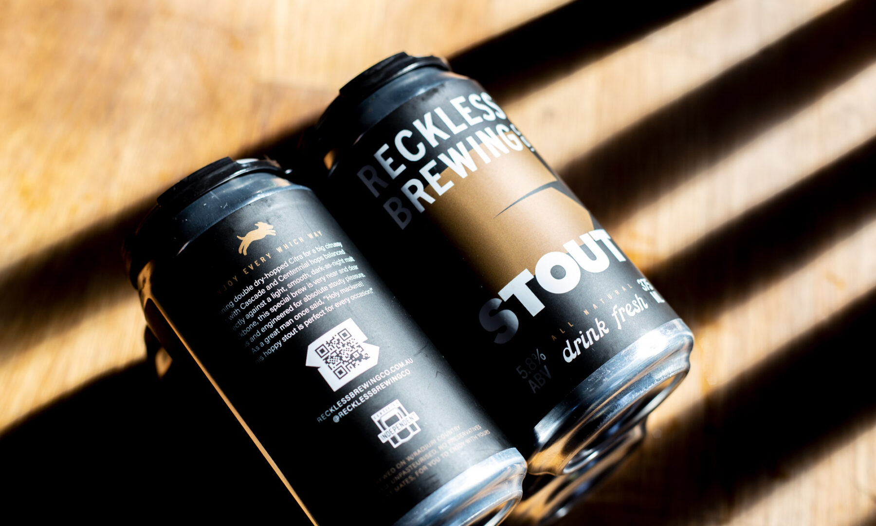Reckless Stout 4 pack on wooden background with heavy shadows